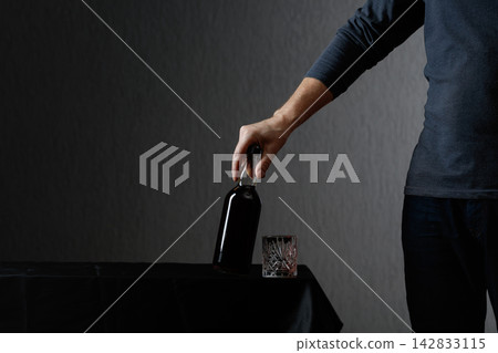 Man picks up a bottle of rum. Man picks up a bottle of rum. 142833115
