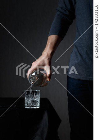 Man pouring strong alcoholic drink in glass. Man pouring strong alcoholic drink in glass. 142833116