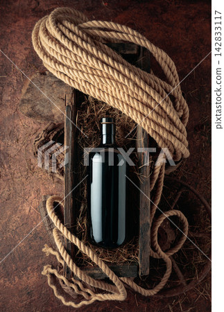 Dark glass bottle of hard liquor in a vintage wooden box. Dark glass bottle of hard liquor in a vintage wooden box. 142833117
