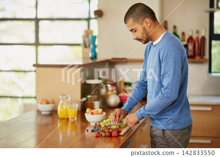 Cooking, man and cutting fruits for breakfast, nutrition or hungry for natural healthy diet in home kitchen. Morning, knife and chopping board for food, organic salad and meal prep with ingredients 142833550