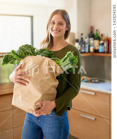 Happy, woman and portrait with vegetables in kitchen for grocery shopping, healthy cooking and eating. Female person, smile and bag of ingredients with spinach or lettuce for nutrition and vegan diet Happy, woman and portrait with vegetables in kitchen for grocery shopping, healthy cooking and eating. Female person, smile and bag of ingredients with spinach or lettuce for nutrition and vegan diet 142834295