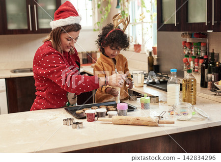 Mother, child and baking with christmas, snack and dough learning for cookies in kitchen together. Smile, food and celebration with woman, adopted son and boy in home to prepare sweet treat or love Mother, child and baking with christmas, snack and dough learning for cookies in kitchen together. Smile, food and celebration with woman, adopted son and boy in home to prepare sweet treat or love 142834296