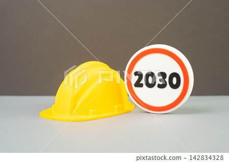 A builder's yellow hard hat and the year 2030. Construction completion deadline by 2030. Deadline. Concept of planning and long term construction project schedules. A builder's yellow hard hat and the year 2030. Construction completion deadline by 2030. Deadline. Concept of planning and long term construction project schedules. 142834328