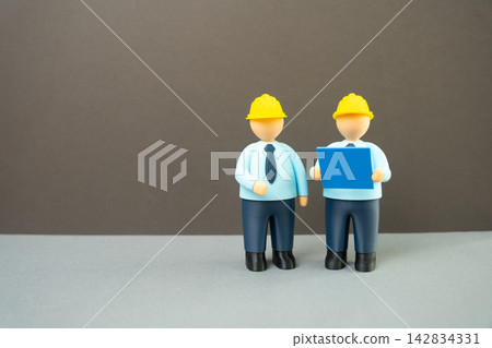 Engineers in yellow hard hats with blueprints. Design and modeling, planning and construction. Concept of teamwork, architecture and engineering projects today. Engineers in yellow hard hats with blueprints. Design and modeling, planning and construction. Concept of teamwork, architecture and engineering projects today. 142834331