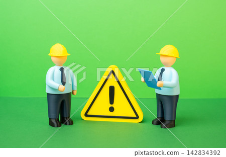 Engineers in yellow hard hats and a warning sign. Detecting and resolving a technical issue. Concept of workplace safety and industrial risk management today. Vigilance. Engineers in yellow hard hats and a warning sign. Detecting and resolving a technical issue. Concept of workplace safety and industrial risk management today. Vigilance. 142834392