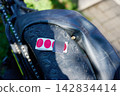 A person is fixing a bicycle tire using a patch and tape. The bike is resting on the ground with green grass nearby 142834414