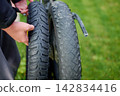 Bicycle mechanic holding new replacement tire for e-bike 142834416