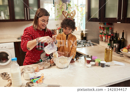 Mother, child and baking with christmas, love and dough learning for cookies in kitchen together. Smile, food and celebration with woman, adopted son and boy in home to prepare sweet treat or snack Mother, child and baking with christmas, love and dough learning for cookies in kitchen together. Smile, food and celebration with woman, adopted son and boy in home to prepare sweet treat or snack 142834417