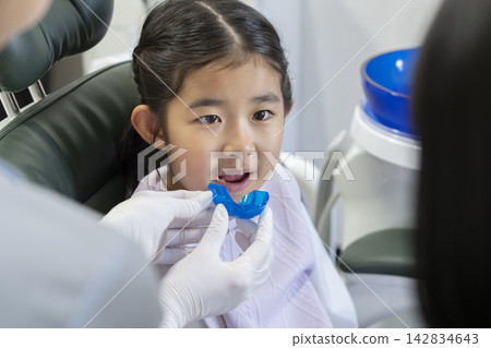 A 6-year-old girl receives an explanation about orthodontic aligners at a dental clinic. A 6-year-old girl receives an explanation about orthodontic aligners at a dental clinic. 142834643