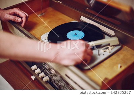 Vinyl record, spinning on turntable, Vintage record player with radio 60's. Male hand placing the needle on vinyl record Vinyl record, spinning on turntable, Vintage record player with radio 60's. Male hand placing the needle on vinyl record 142835297