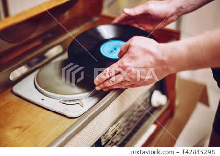 Vinyl record, spinning on turntable, Vintage record player with radio 60's. Mens hands putting vintage record in vinyl player Vinyl record, spinning on turntable, Vintage record player with radio 60's. Mens hands putting vintage record in vinyl player 142835298