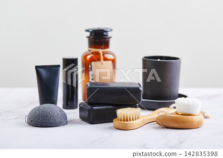 Three pieces of black charcoal soap, Konjac sponge, beauty care products, candles and brushes for washing and massage on marble background Three pieces of black charcoal soap, Konjac sponge, beauty care products, candles and brushes for washing and massage on marble background 142835398