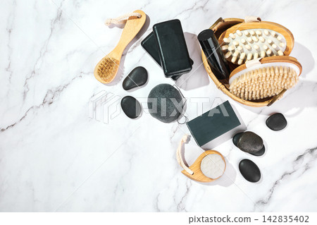 Three pieces of black charcoal soap, Konjac sponge, beauty care products, candles and brushes for washing and massage on marble background Three pieces of black charcoal soap, Konjac sponge, beauty care products, candles and brushes for washing and massage on marble background 142835402