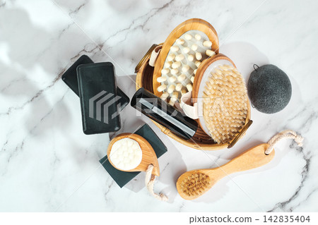 Three pieces of black charcoal soap, Konjac sponge, beauty care products, candles and brushes for washing and massage on marble background Three pieces of black charcoal soap, Konjac sponge, beauty care products, candles and brushes for washing and massage on marble background 142835404