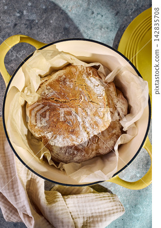 Freshly baked rustic bread in yellow cast iron Dutch oven Freshly baked rustic bread in yellow cast iron Dutch oven 142835708