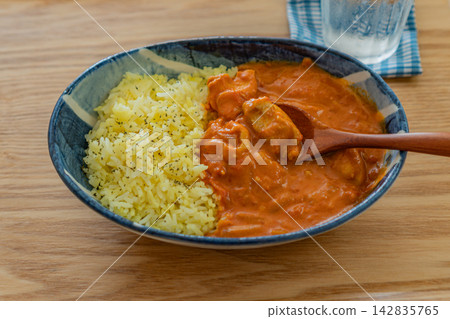 Enjoy chicken curry and saffron rice at a large wooden table. Enjoy chicken curry and saffron rice at a large wooden table. 142835765