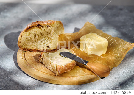 Spreading butter on fresh rustic sourdough bread slice Spreading butter on fresh rustic sourdough bread slice 142835899