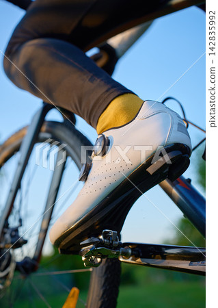 Cyclist wearing cycling shoe clipped into bicycle pedal 142835992