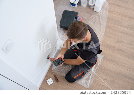 Electrician checking wall socket wiring with multimeter Electrician checking wall socket wiring with multimeter 142835994