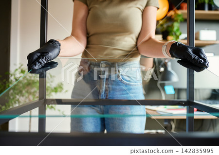 Woman installing glass shelf into metal shelving unit Woman installing glass shelf into metal shelving unit 142835995