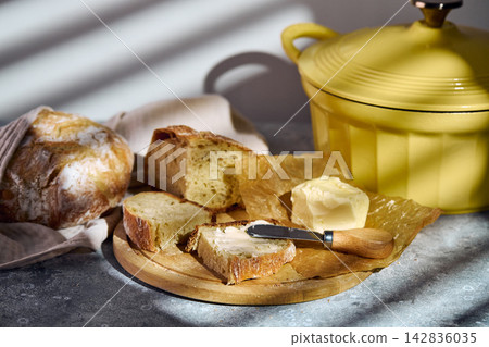 Spreading butter on fresh rustic sourdough bread slice Spreading butter on fresh rustic sourdough bread slice 142836035
