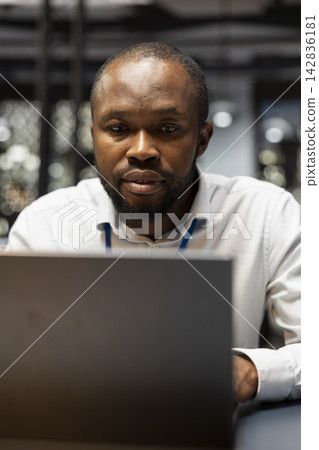 Evaluating operational metrics, laptop and worker at office desk. Working late at night, notebook device and African american staff member assisting online clients, finishing tasks Evaluating operational metrics, laptop and worker at office desk. Working late at night, notebook device and African american staff member assisting online clients, finishing tasks 142836181