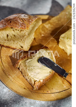 Spreading butter on fresh rustic sourdough bread slice Spreading butter on fresh rustic sourdough bread slice 142836244