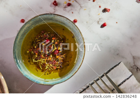 Olive oil with herbs and spices in blue ceramic bowl Olive oil with herbs and spices in blue ceramic bowl 142836248
