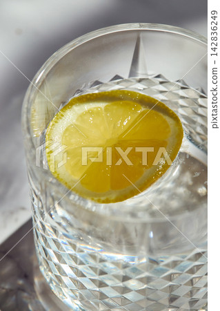 Close-up of a fresh lemon slice floating in a crystal glass of water 142836249
