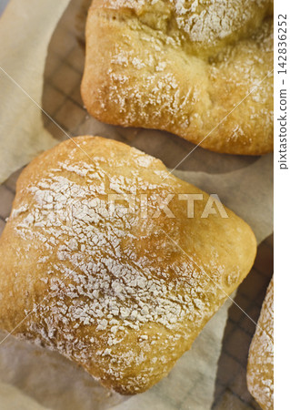 Close-up of homemade mini ciabatta rolls dusted with flour on parchment paper Close-up of homemade mini ciabatta rolls dusted with flour on parchment paper 142836252