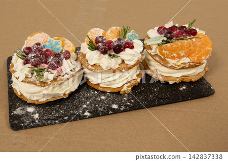 Three sweet desserts with cream and fruit placed on a black slate board ready for a gathering or event Three sweet desserts with cream and fruit placed on a black slate board ready for a gathering or event 142837338