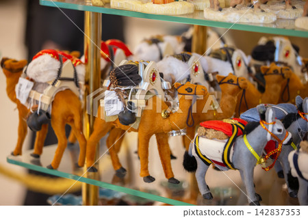 A collection of handcrafted camel figurines displayed at a market during the daytime at an oriental market A collection of handcrafted camel figurines displayed at a market during the daytime at an oriental market 142837353