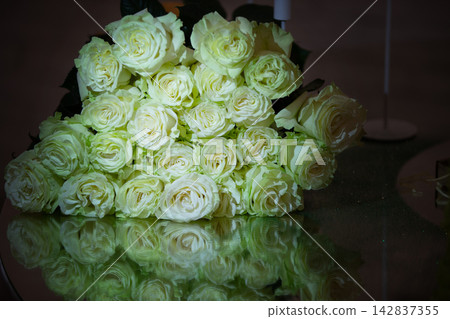White roses arranged on a reflective surface in a dimly lit space during a special occasion White roses arranged on a reflective surface in a dimly lit space during a special occasion 142837355