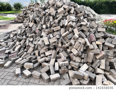 Pile of old concrete paving slabs removed from street. Road repair and sidewalk renovation concept. Used paving stones stacked for recycling and reuse in landscaping. Pile of old concrete paving slabs removed from street. Road repair and sidewalk renovation concept. Used paving stones stacked for recycling and reuse in landscaping. 142838036