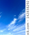 White, trailing cirrus clouds spread across the clear blue autumn sky. 142838292