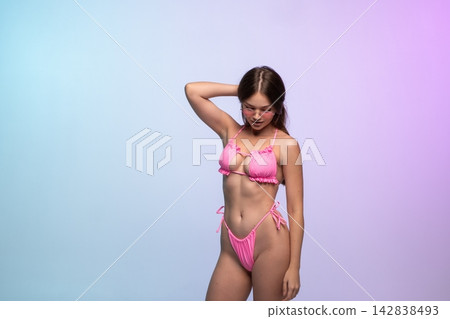 Woman posing in a pink string bikini and sunglasses, embracing summer fashion and swimwear on a vibrant studio background Woman posing in a pink string bikini and sunglasses, embracing summer fashion and swimwear on a vibrant studio background 142838493