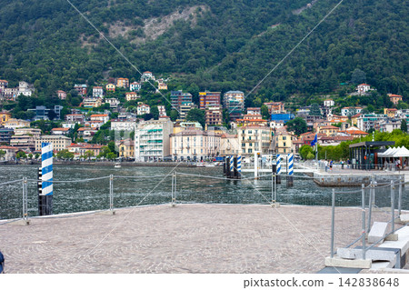 Lake Como Waterfront Promenade with Ferry Terminal Building and City Buildings Italy Lake Como Waterfront Promenade with Ferry Terminal Building and City Buildings Italy 142838648