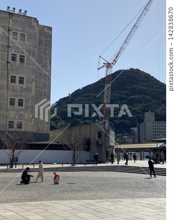 一家人在車站廣場拍照,背景是正在施工的起重機。 一家人在車站廣場拍照,背景是正在施工的起重機。 142838670