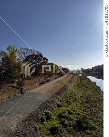 A riverside promenade in Kyoto, where autumn trees and a clear blue sky stretch out above. A riverside promenade in Kyoto, where autumn trees and a clear blue sky stretch out above. 142838700