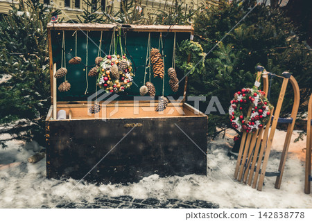 MOSCOW, RUSSIA 28 DEC 2018. Large chest with wreath and decorative vintage sleigh for gifts surrounded by Christmas trees. Christmas celebration and fairy on Red Square. New year. MOSCOW, RUSSIA 28 DEC 2018. Large chest with wreath and decorative vintage sleigh for gifts surrounded by Christmas trees. Christmas celebration and fairy on Red Square. New year. 142838778
