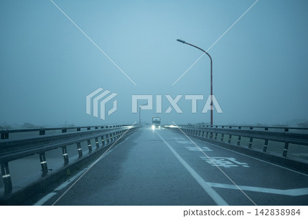 瓢潑大雨中,橋上的公路蜿蜒而過,遠處有一輛卡車駛過。 瓢潑大雨中,橋上的公路蜿蜒而過,遠處有一輛卡車駛過。 142838984
