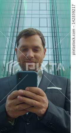 Vertical video. Young Professional Using Smartphone Near Business Center. Vertical video. Young Professional Using Smartphone Near Business Center. 142839217