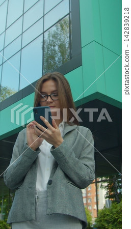 Vertical video. Young Businesswoman Using Mobile Phone Near Business Center. Vertical video. Young Businesswoman Using Mobile Phone Near Business Center. 142839218
