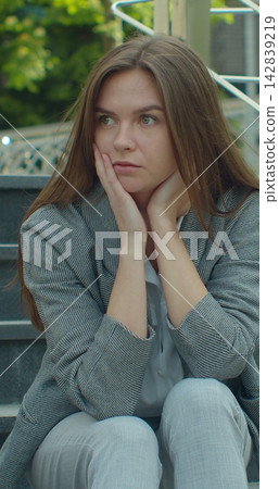 Vertical video. Businesswoman sitting on stairs near office center with carton box and documents with a table flower as lost job. Female office worker in despair lost job. Unemployment rate growing Vertical video. Businesswoman sitting on stairs near office center with carton box and documents with a table flower as lost job. Female office worker in despair lost job. Unemployment rate growing 142839219