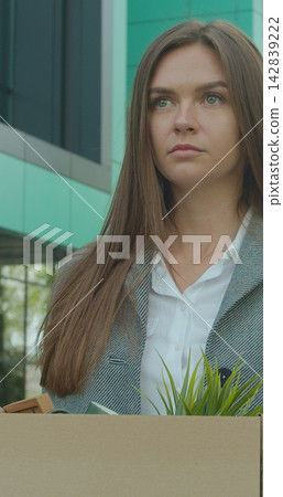 Vertical video. Emotional disappointed Corporate worker gets fired and walking near office center with carton box and documents with a table flower. Lost His Job. Unemployment rate growing due Vertical video. Emotional disappointed Corporate worker gets fired and walking near office center with carton box and documents with a table flower. Lost His Job. Unemployment rate growing due 142839222