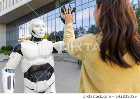 Humanoid robot giving high five to young woman Humanoid robot giving high five to young woman 142839359