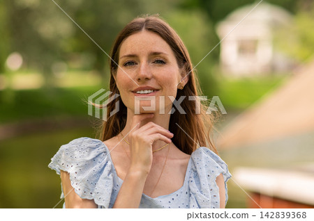 Pretty young beaming woman in a light dress in the park Pretty young beaming woman in a light dress in the park 142839368