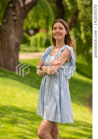 Pretty young beaming woman in a light dress in the park Pretty young beaming woman in a light dress in the park 142839370