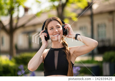 Waist up of a pretty young caucasian woman in headphones Waist up of a pretty young caucasian woman in headphones 142839420