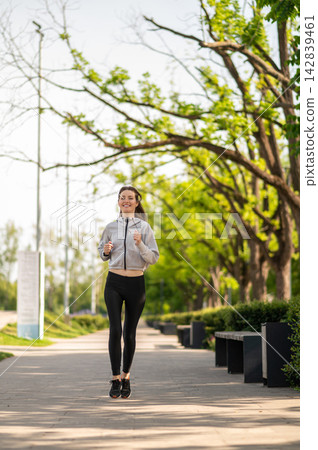 Young slim woman running on a greenery background Young slim woman running on a greenery background 142839461